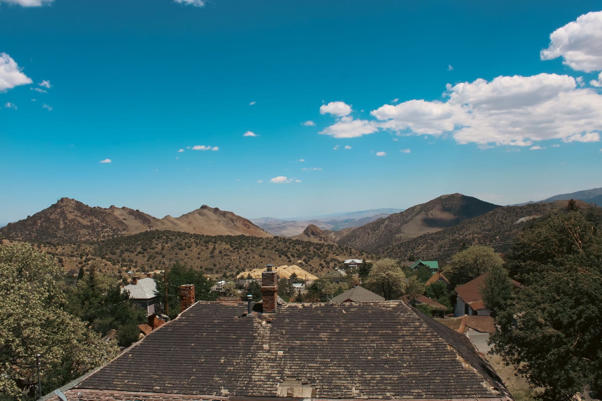Rooftops of Virginia City, Nevada set against the bare Comstock hillsides of the Virginia Range under a clear sky.