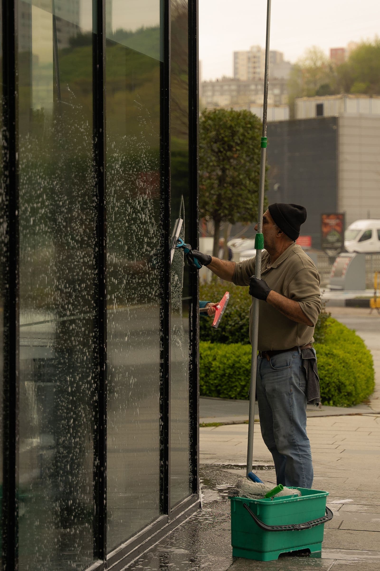 Professional window cleaner squeegeeing soap from a commercial glass facade, the storefront work Still Window Co does across Northern Nevada.
